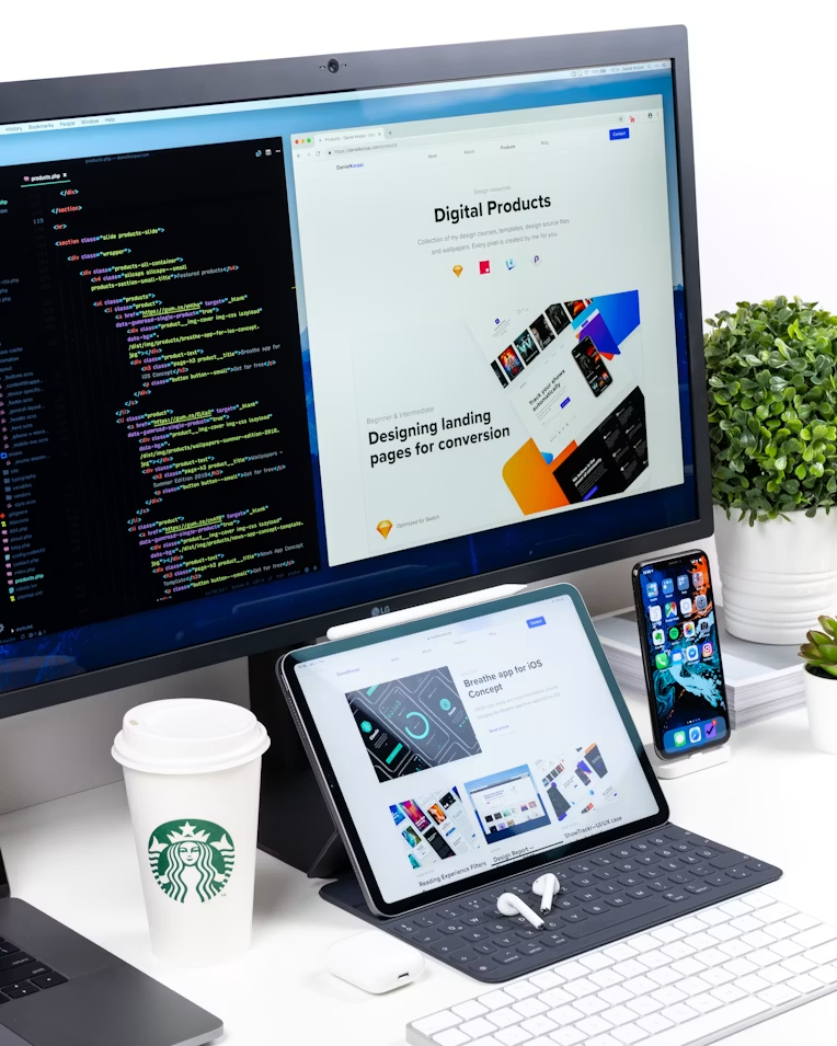 A developer's desk setup with code and product design work across a monitor, tablet, and phone
